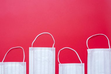 Kırmızı arka planda tıbbi yüz maskesi, koronavirüsü veya Corona Virüs Hastalığını önlemek (Covid-19). yeni normal ve sağlık kavramı