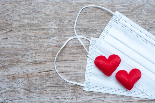 heart shape decoration and Medical face mask on table background against Coronavirus disease infection. Love, together and Happy Valentines day under Covid-19 pandemic concept