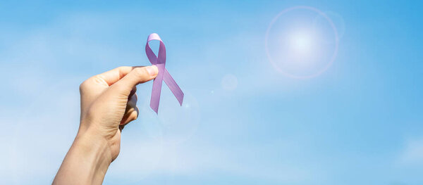 World cancer day (February 4). Woman hand holding Lavender purple ribbon for supporting people living and illness. Healthcare and medical concept