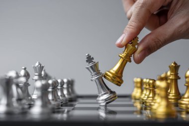 Satranç tahtası yarışmasında işadamı eli altın satranç kralı figürü ve şah mat enerjisi ya da rakibi. Strateji, Başarı, Yönetim, İş Planlama, Bölünme ve liderlik kavramı