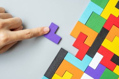 Geometrik şekil bloğunu renkli ahşap yapboz parçalarıyla birleştiren el. Mantıklı düşünme, iş mantığı, Bilmece, karar, çözümler, rasyonel, misyon, başarı, hedefler ve strateji kavramları