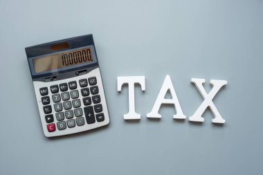 Gri arkaplan üzerinde hesap makinesi olan vergi metni. Yatırım ve vergi kavramları için zaman