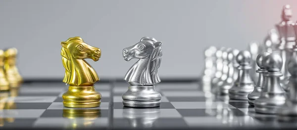 Gold and silver Chess Knight (horse) figure on Chessboard against opponent or enemy. Strategy, Conflict, management, business planning, tactic, politic, communication and leader concept