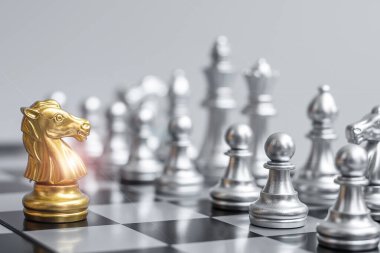 Satranç tahtasındaki Altın Satranç Şövalyesi (at) rakip ya da düşmana karşı. Strateji, çatışma, yönetim, iş planlaması, taktik, siyaset, iletişim ve lider konsepti