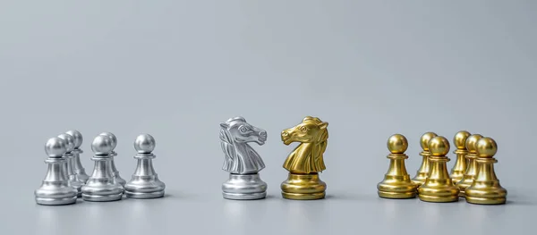 Gold and silver Chess Knight (horse) figure on Chessboard against opponent or enemy. Strategy, Conflict, management, business planning, tactic, politic, communication and leader concept