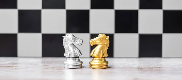 Gold and silver Chess Knight (horse) figure on Chessboard against opponent or enemy. Strategy, Conflict, management, business planning, tactic, politic, communication and leader concept