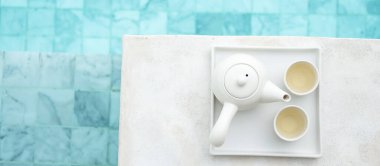 Lüks oteldeki yüzme havuzunun yanında sıcak çay demliği. Yaz seyahati, tatil, tatil ve hafta sonu konsepti