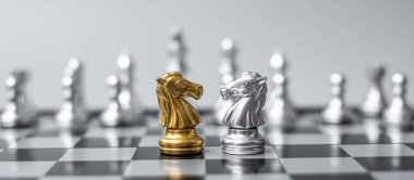 Satranç tahtasındaki altın ve gümüş satranç şövalyesi (at) rakip ya da düşmana karşı. Strateji, çatışma, yönetim, iş planlaması, taktik, siyaset, iletişim ve lider konsepti