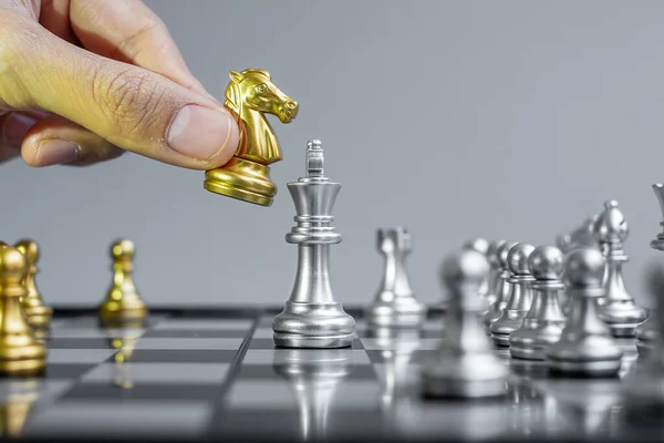 businessman hand moving gold Chess Knight figure and Checkmate opponent during chessboard competition. Strategy, Success, management, business planning, disruption and leadership concept