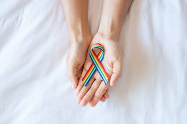Beyaz yatak arka planında LGBTQ Gökkuşağı kurdelesini gösteriyor. Lezbiyen, Eşcinsel, Biseksüel, Transseksüel, Eşcinsel Topluluğu ve Hakları Destekleme Konsepti
