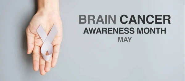 Brain Cancer Awareness month, woman hand holding grey color Ribbon for supporting people living. Healthcare and World cancer day concept