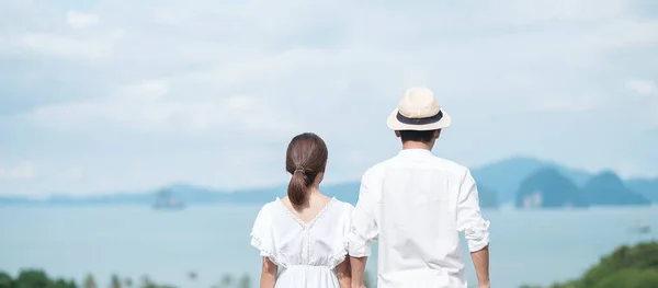 Happy couple traveler in white shirt and dress enjoy Beautiful view, Tourists with standing and relaxing over ocean. travel, together, love, summer and vacation concept
