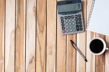 Hesap makinesi, kalem, boş defter ve ahşap masa arkasında kahve fincanı olan üst kat ofis masası. metin kavramı için kopyalama alanı olan çalışma alanı veya ev ofisi