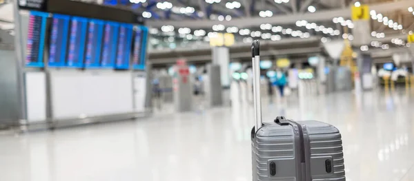 luggage bag in international airport terminal, trolley suitcase with information board in aerodrome background. Transport, insurance, travel and vacation concepts