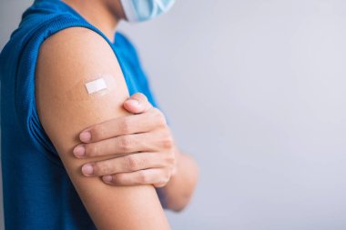 Aşı olduktan sonra kolunu bandajla gösteren mutlu bir adam. Aşı, aşı, aşı, aşı ve Coronavirüs (Covid-19) salgını