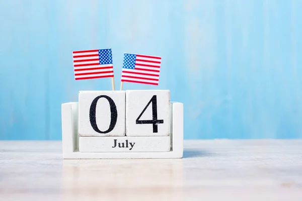 木製の背景にミニチュアアメリカ国旗と7月4日の木製のカレンダー 独立記念日と国民の休日の概念 — ストック写真