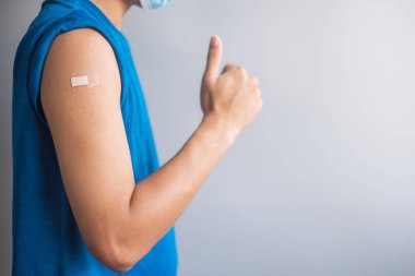 Aşı olduktan sonra kolunu bandajla gösteren mutlu bir adam. Aşı, aşı, aşı, aşı ve Coronavirüs (Covid-19) salgını