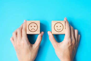 Elele tutuşan bir adam yüz bloğu. Müşteri, kullanıcı değerlendirmeleri için Emoticon 'u seçer. Hizmet derecesi, sıralama, müşteri değerlendirmesi, memnuniyet, değerlendirme ve geri bildirim kavramı