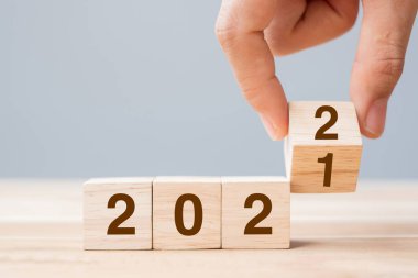 İş adamı, masa arkasında 2021 'den 2022' ye kadar yazı yazan tahta küpü tutuyor. Çözüm, strateji, çözüm, hedef, iş ve yeni yıl tatili kavramları