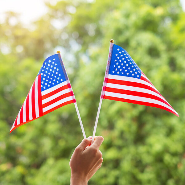 hand holding United States of America flag on green background. USA holiday of Veterans, Memorial, Independence ( Fourth of July) and Labor Day concept