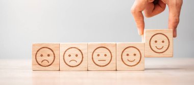 Elele tutuşan bir adam yüz bloğu. Müşteri, kullanıcı değerlendirmeleri için Emoticon 'u seçer. Hizmet derecesi, sıralama, müşteri değerlendirmesi, memnuniyet, değerlendirme ve geri bildirim kavramı