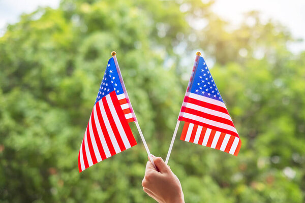 hand holding United States of America flag on green background. USA holiday of Veterans, Memorial, Independence ( Fourth of July) and Labor Day concept