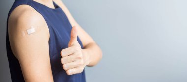 Covid 19 aşısından sonra başparmağını bandajla gösteren mutlu bir kadın. Aşı, sürü bağışıklığı, yan etki, verimlilik, aşı pasaportu ve Coronavirus salgını.