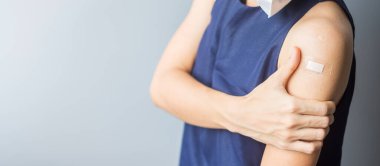 Kolunu bandajla gösteren bir kadın. 19 numaralı aşıyı aldıktan sonra. Aşı, sürü bağışıklığı, yan etki, aşı verimliliği ve Coronavirus salgını.