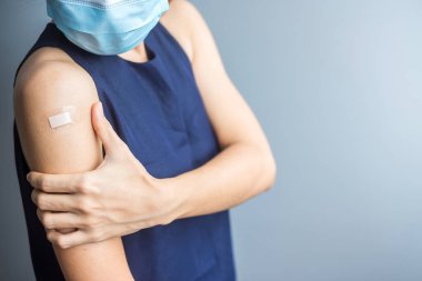 Kolunu bandajla gösteren bir kadın. 19 numaralı aşıyı aldıktan sonra. Aşı, sürü bağışıklığı, yan etki, aşı verimliliği ve Coronavirus salgını.