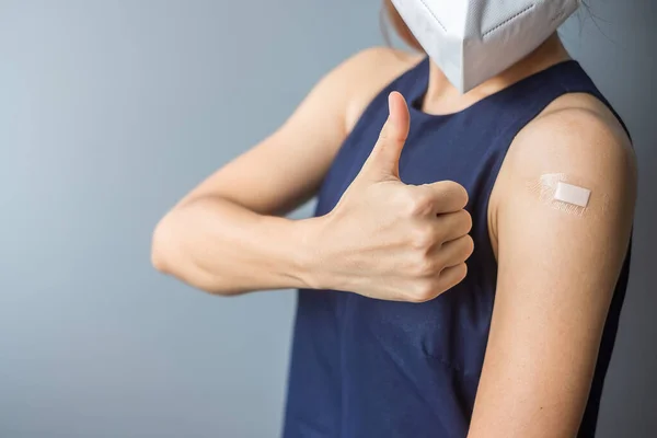 Happy woman showing thumb with bandage after receiving covid 19 vaccine. Vaccination, herd immunity, side effect, efficiency, vaccine passport and Coronavirus pandemic