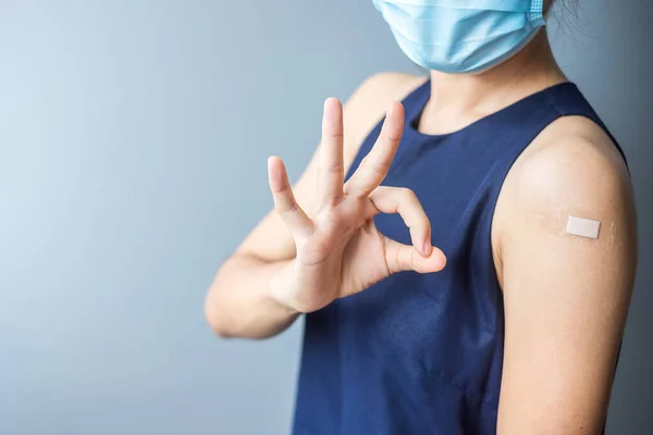 Happy woman showing OK sign with bandage after receiving covid 19 vaccine. Vaccination, herd immunity, side effect, efficiency, vaccine passport and Coronavirus pandemic