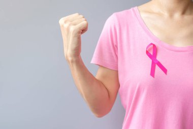 Ekim Kanser Farkındalık Ayı, pembe tişörtlü yaşlı kadın ve Pembe kurdeleli ve yaşayan ve hastalıkları destekleyen yumruk işareti. Uluslararası Kadınlar, Anne ve Dünya Kanser Günü Konsepti