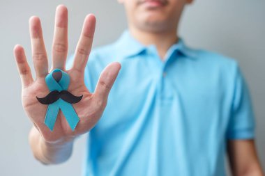 November Prostate Cancer Awareness month, Man holding Blue Ribbon with mustache for supporting people living and illness. Healthcare, International men, Father and World cancer day concept clipart