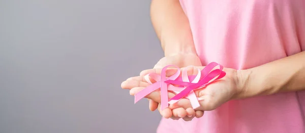 October Breast Cancer Awareness month, elderly Woman in pink T- shirt with hand holding Pink Ribbon for supporting people living and illness. International Women, Mother and World cancer day concept