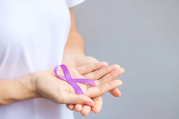 Hand holding purple Ribbon for Pancreatic, Esophageal, Testicular cancer, world Alzheimer, epilepsy, lupus, Sarcoidosis, Fibromyalgia and domestic violence Awareness month. World cancer day concept