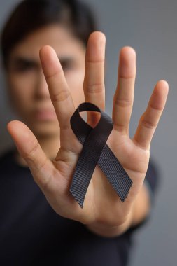 Melanoma ve cilt kanseri için siyah kurdele tutan kadın, Aşı yaralanması farkındalığı ayı, keder ve huzur içinde yatsın. Sağlık ve Irkçılık Konsepti