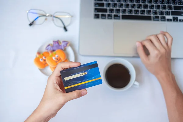 Handhållning Kreditkort För Online Shopping Laptop Äta Halloween Cookies Och — Stockfoto