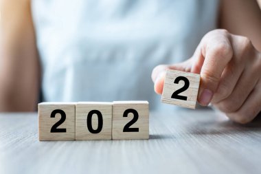 İş kadını, masa arkasında 2022 metni olan tahta küpü tutuyor. Çözüm, strateji, çözüm, hedef, iş, Yeni Yıl Yeni Sen ve mutlu tatil kavramları