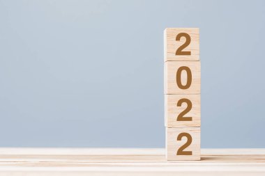 Masa arkasında 2022 tahta küp blok var. Çözüm, plan, gözden geçirme, hedef, başlangıç ve yeni yıl tatili kavramları