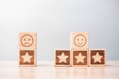 Masa arkasındaki duygu yüz ve yıldız sembolü blokları. Hizmet derecesi, sıralama, müşteri değerlendirmesi, memnuniyet, değerlendirme ve geri bildirim kavramı