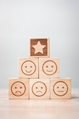 Masa arkasındaki duygu yüz ve yıldız sembolü blokları. Hizmet derecesi, sıralama, müşteri değerlendirmesi, memnuniyet, değerlendirme ve geri bildirim kavramı