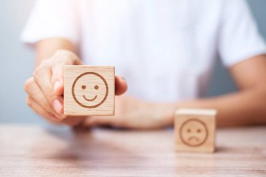 Elele tutuşan bir adam yüz bloğu. Müşteri, kullanıcı değerlendirmeleri için Emoticon 'u seçer. Hizmet derecesi, sıralama, müşteri değerlendirmesi, memnuniyet, değerlendirme ve geri bildirim kavramı