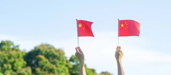 青い空の背景に中国国旗を掲げて手をつなぐ 中華人民共和国のナショナルデー 国民の祝日と幸せなお祝いの概念 — ストック写真