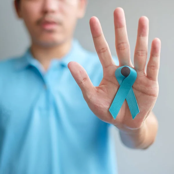 November Prostate Cancer Awareness month, Man in blue shirt with hand holding Blue Ribbon for supporting people living and illness. Healthcare, International men, Father and World cancer day concept