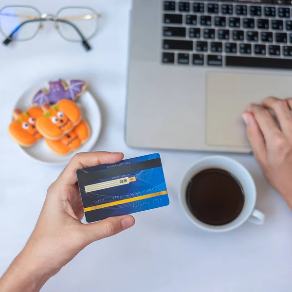 Handhållning Kreditkort För Online Shopping Laptop Äta Halloween Cookies Och — Stockfoto