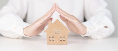 Kadın el kapağı ahşap ev modeli. Gayrimenkul, sigorta ve mülkiyet kavramları