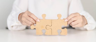 Yapboz parçaları birleştiren kadın, masa üzerinde tahta yapboz. İş çözümleri, misyon, başarı, hedefler, strateji, takım çalışması, fikir, çözüm ve meydan okuma kavramları