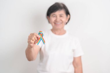 Haziran Gurur Ayı, Nisan Otizm Bilinci, Kanser Farkındalığı, Şubat Dünya Kanser Günü, Ekim Dünya Bakımevi ve Palyatif Bakım Günü konsepti için LGBTQ Gökkuşağı kurdelesine sahip yaşlılar