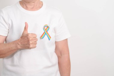 Haziran Gurur Ayı, Nisan Otizm Bilinci, Kanser Farkındalığı, Şubat Dünya Kanser Günü, Ekim Dünya Bakımevi ve Palyatif Bakım Günü konsepti için LGBTQ Gökkuşağı kurdelesine sahip yaşlılar