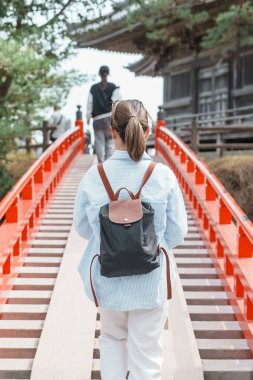Zuiganji Godaido 'ya giden Sukashibashi köprüsünden geçen bir kadın turist veya Matsushima, Miyagi Bölgesi, Tohoku, Japonya' daki Matsushima Körfezi 'ndeki küçük bir tapınak binası.